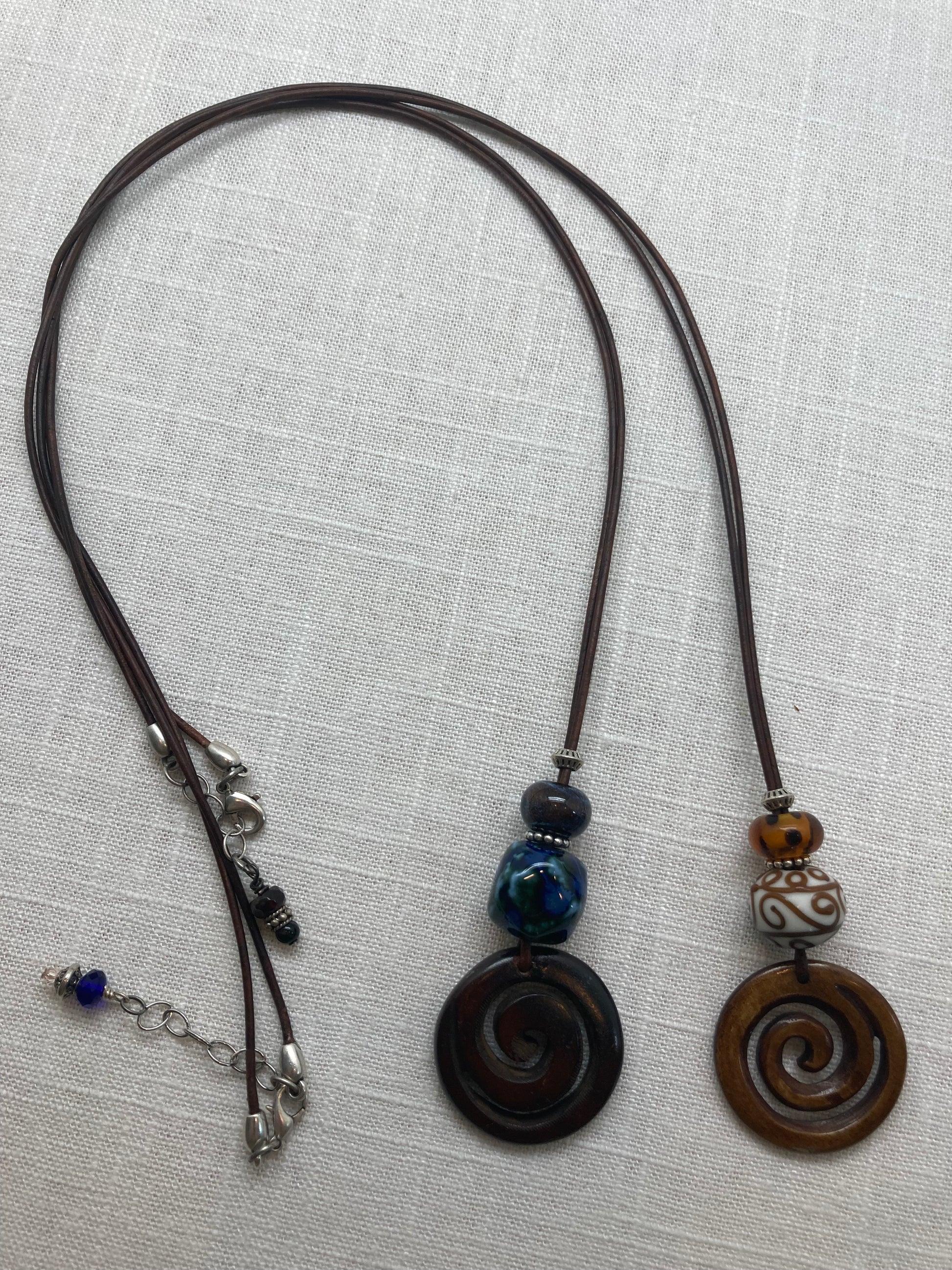 dark brown leather necklaces with spiral carved wooden pendants and glass beads