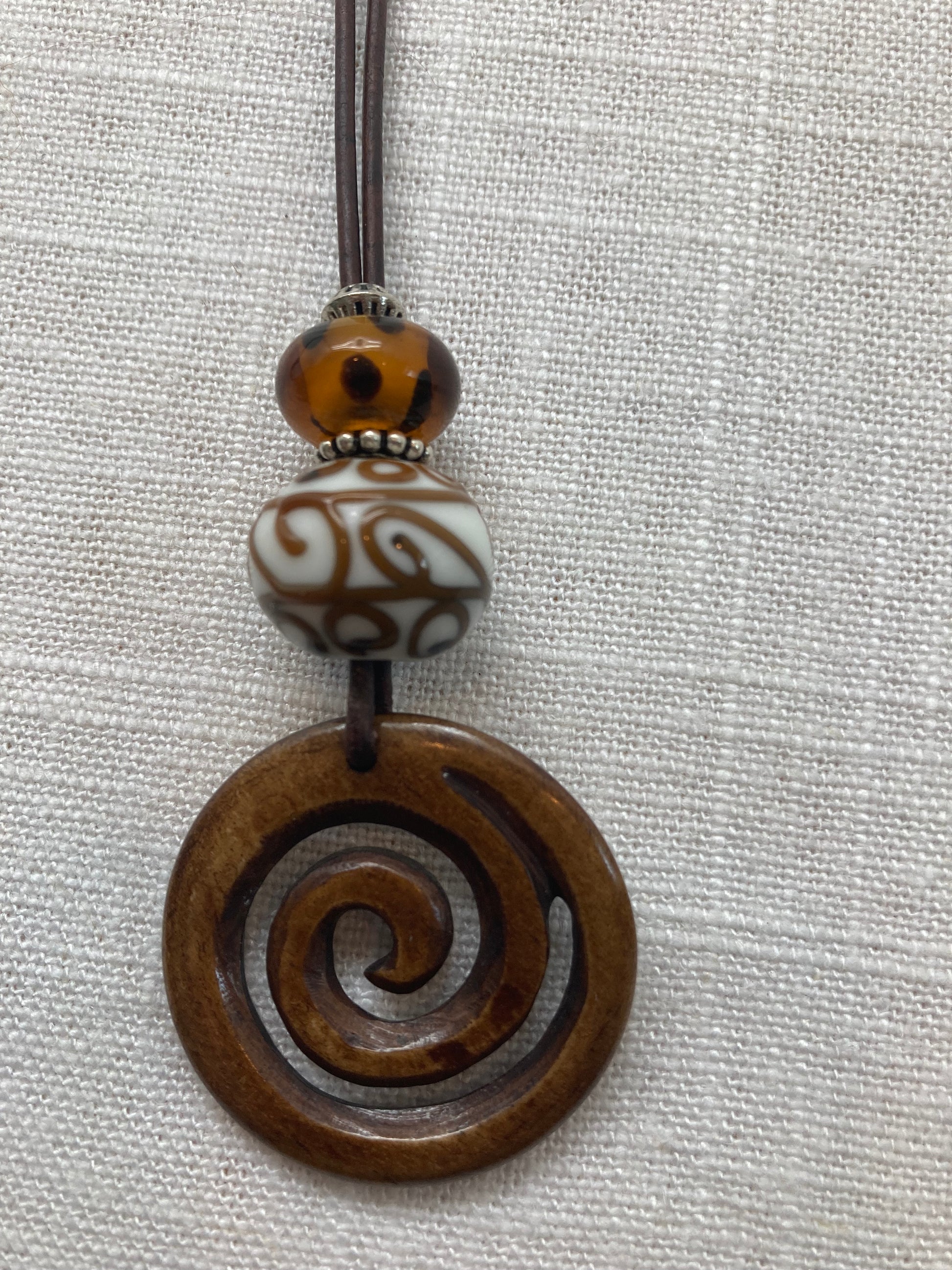 brown leather necklace with brown glass beads and carved wood swirl