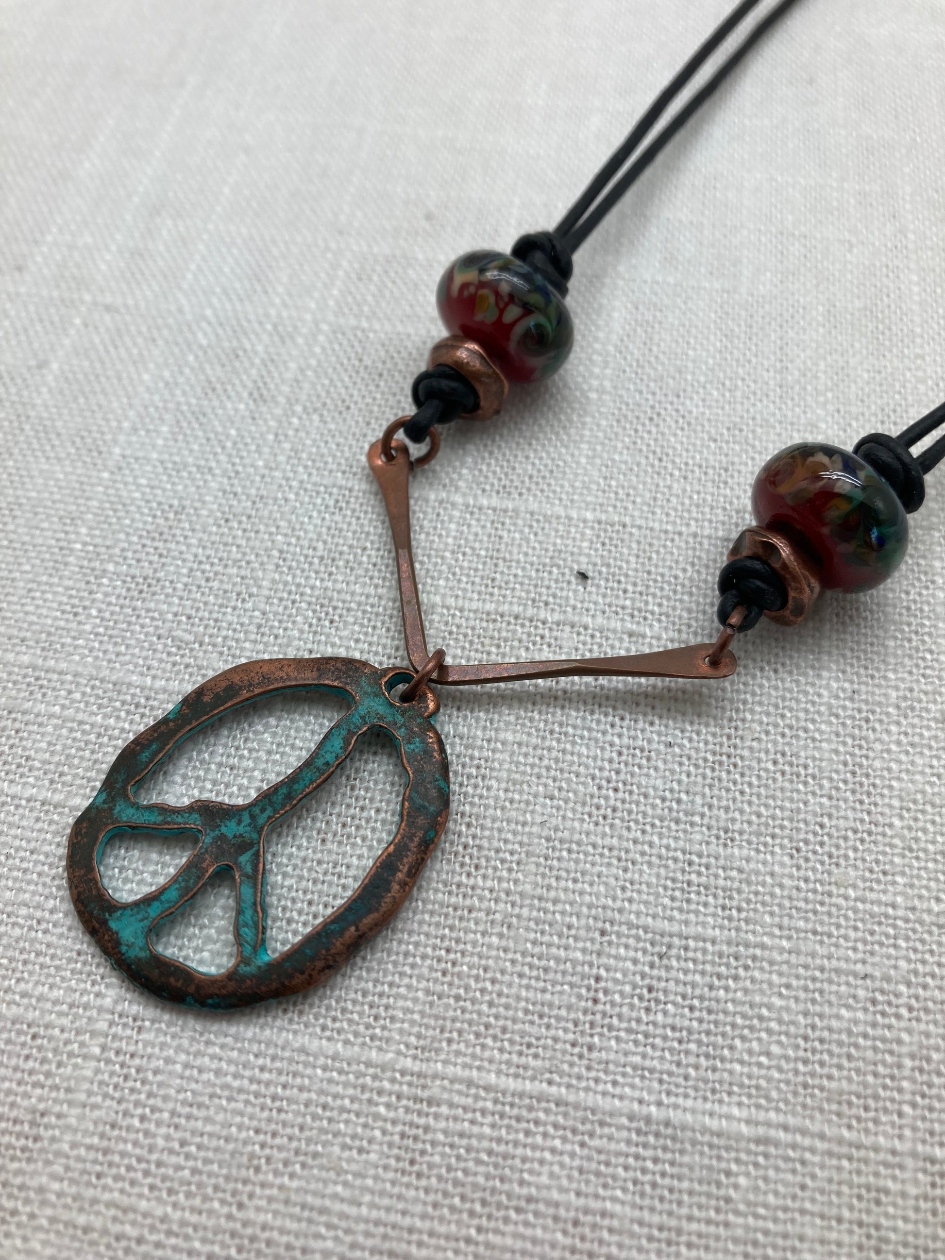 leather necklace with blue-green peace sign