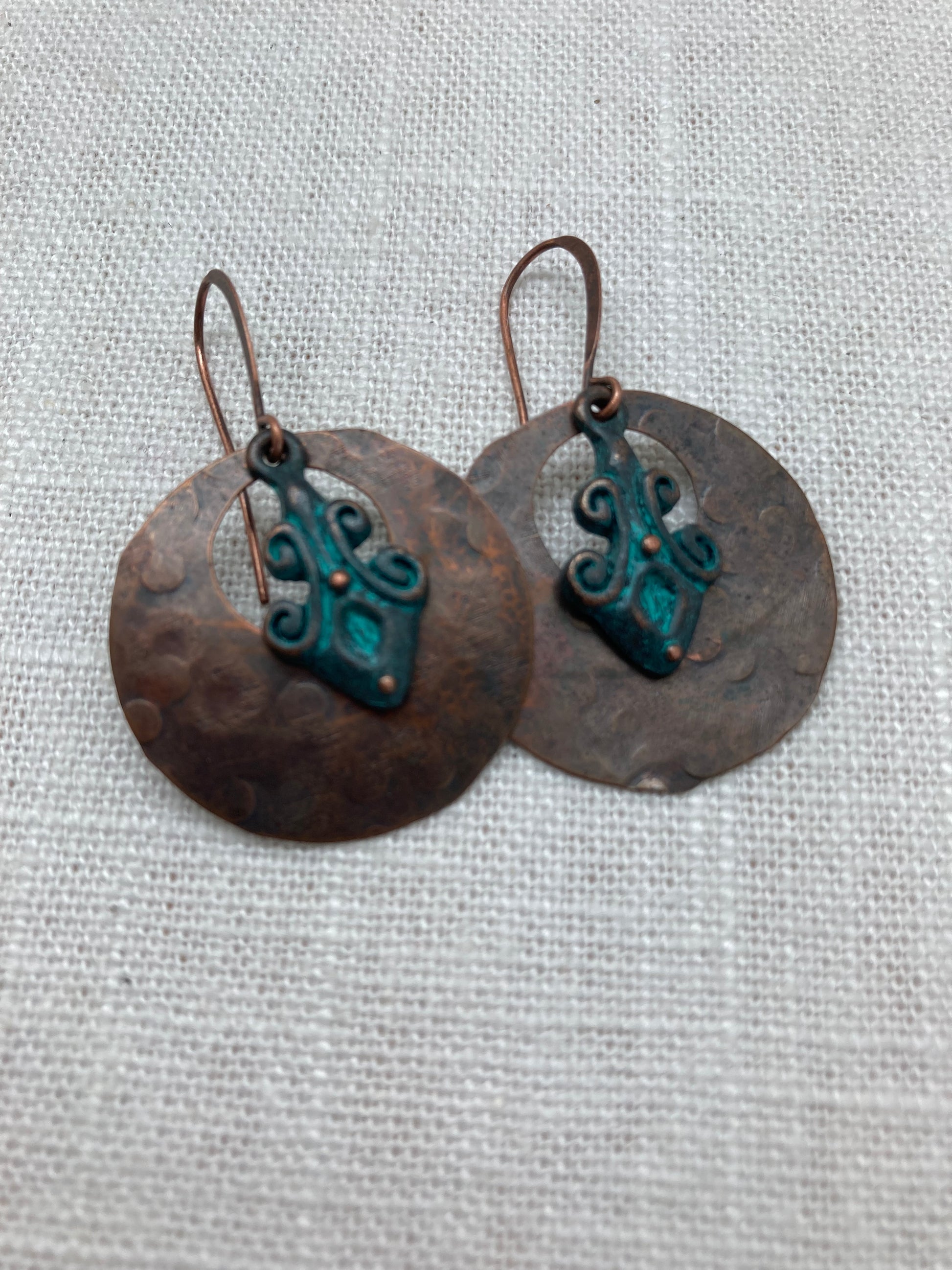 ring shaped hammered copper earrings with patina fleur-shaped charm